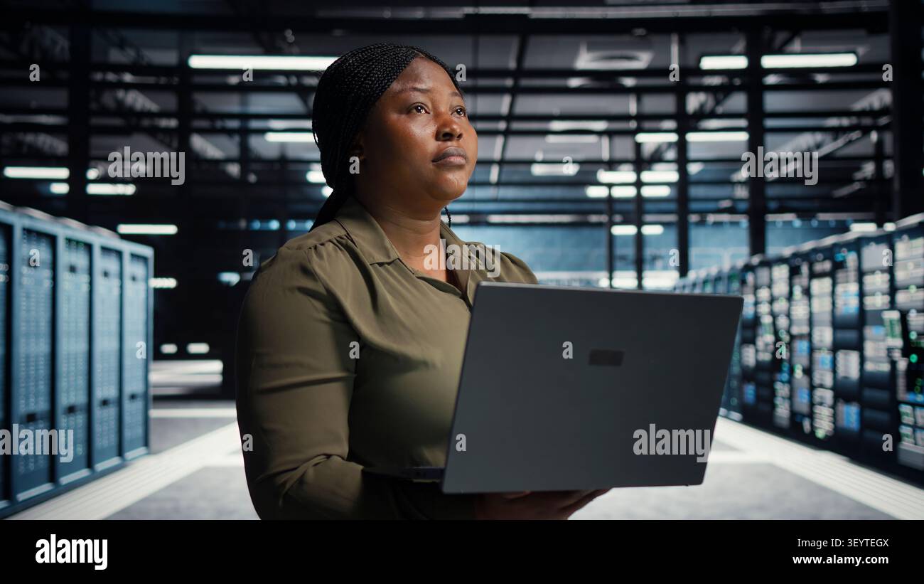 Technical specialist working with notebook computer in advanced technology server facility, integrating new technologies and systems. Stock Photo