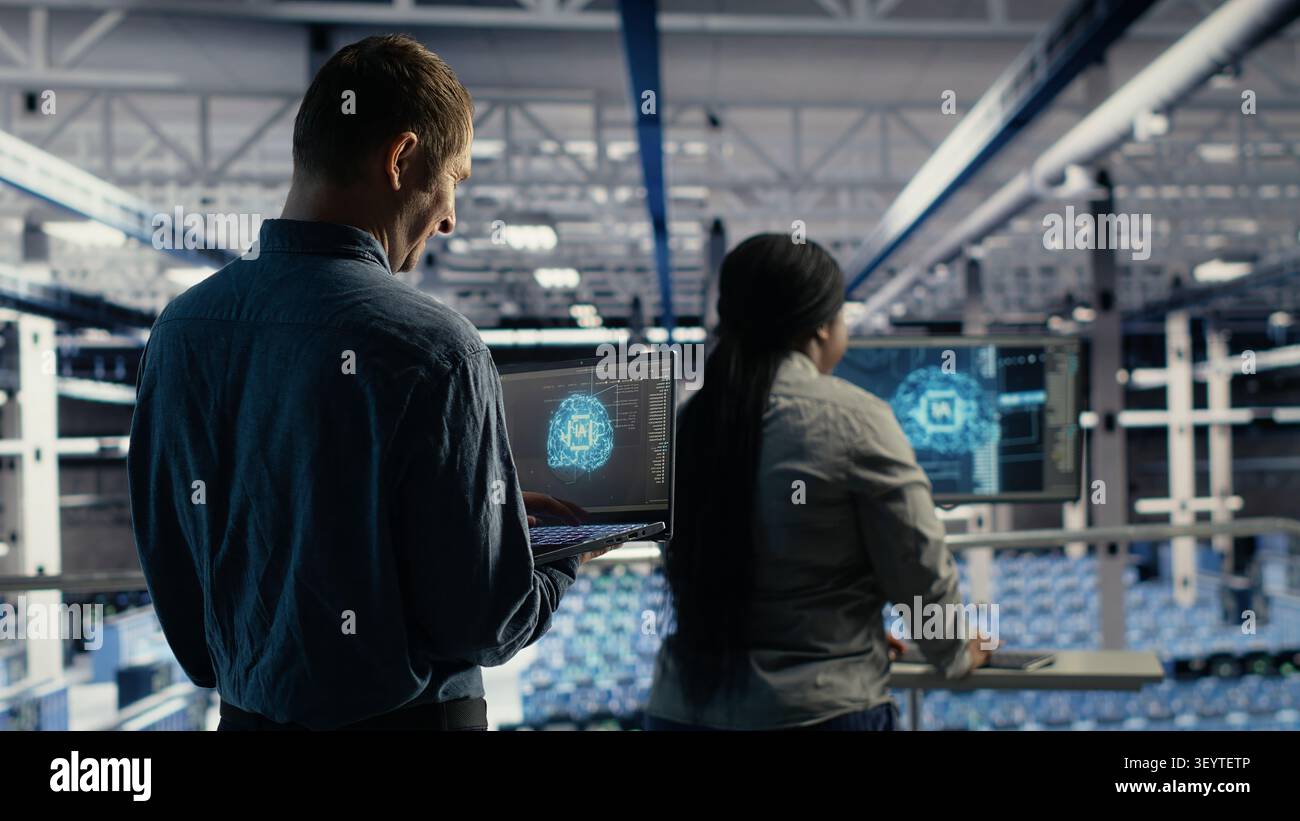 IT colleagues collaborate in a data center while reviewing AI diagnostics and infrastructure performance. Stock Photo