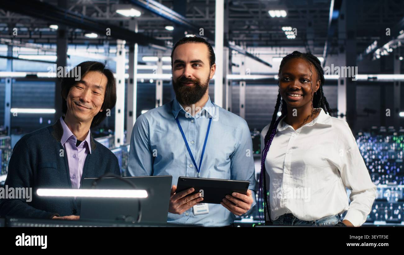 Smiling engineers in a server room review AI diagnostics and performance data together. Stock Photo