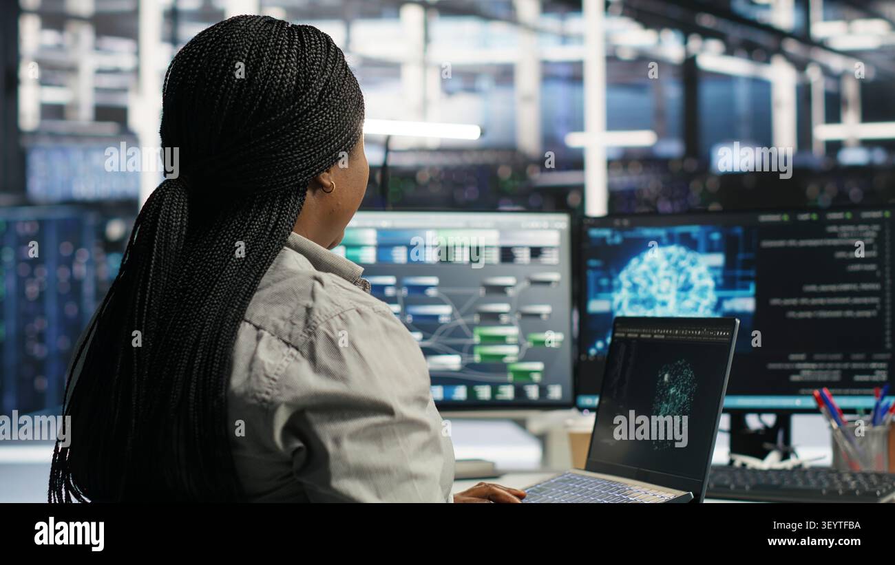 Data center administrator uses a laptop to manage machine learning workloads, working with AI technology and high performance systems. Stock Photo