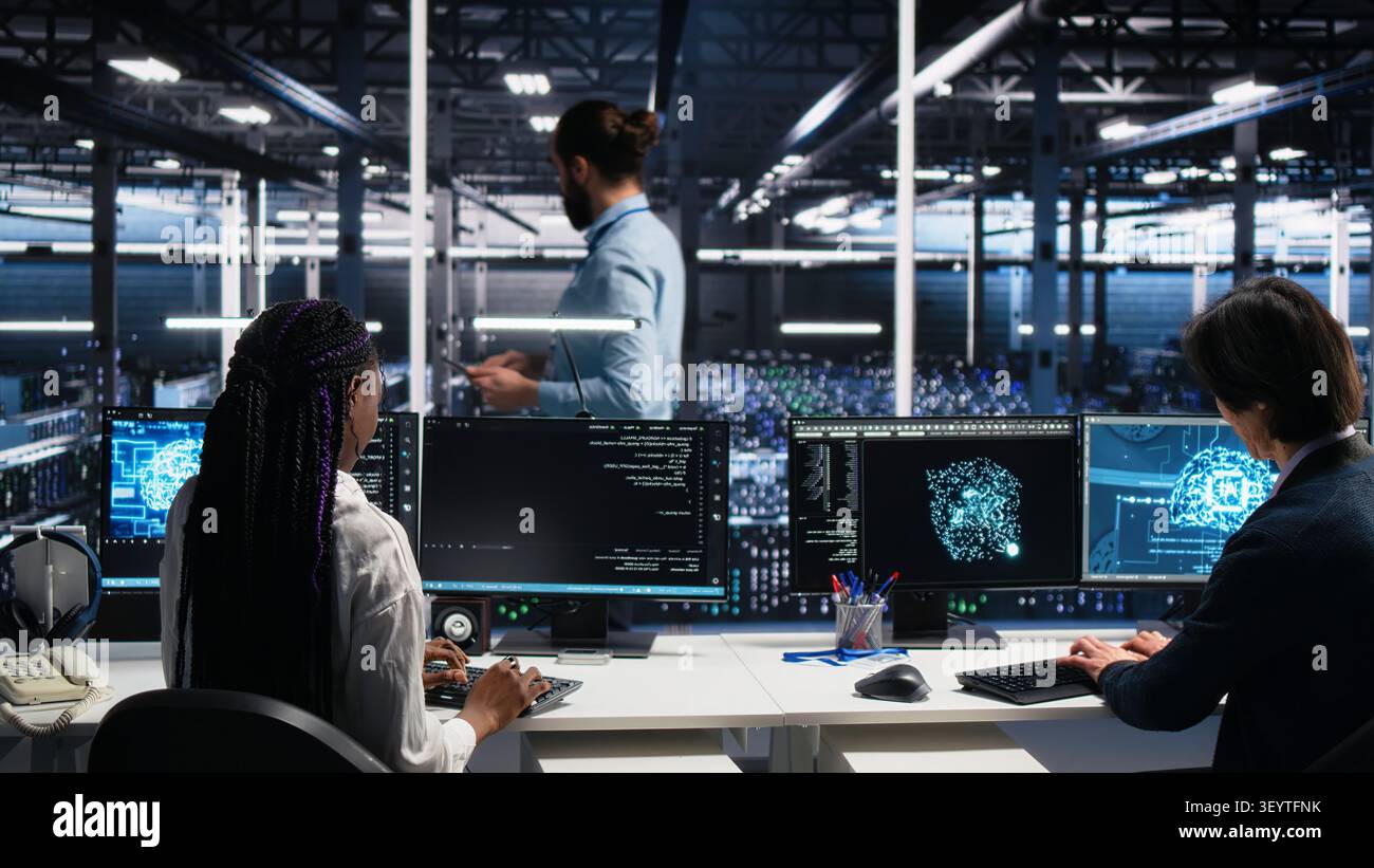 Server room manager checking work done by admins working with deep learning to review data sets. Stock Photo