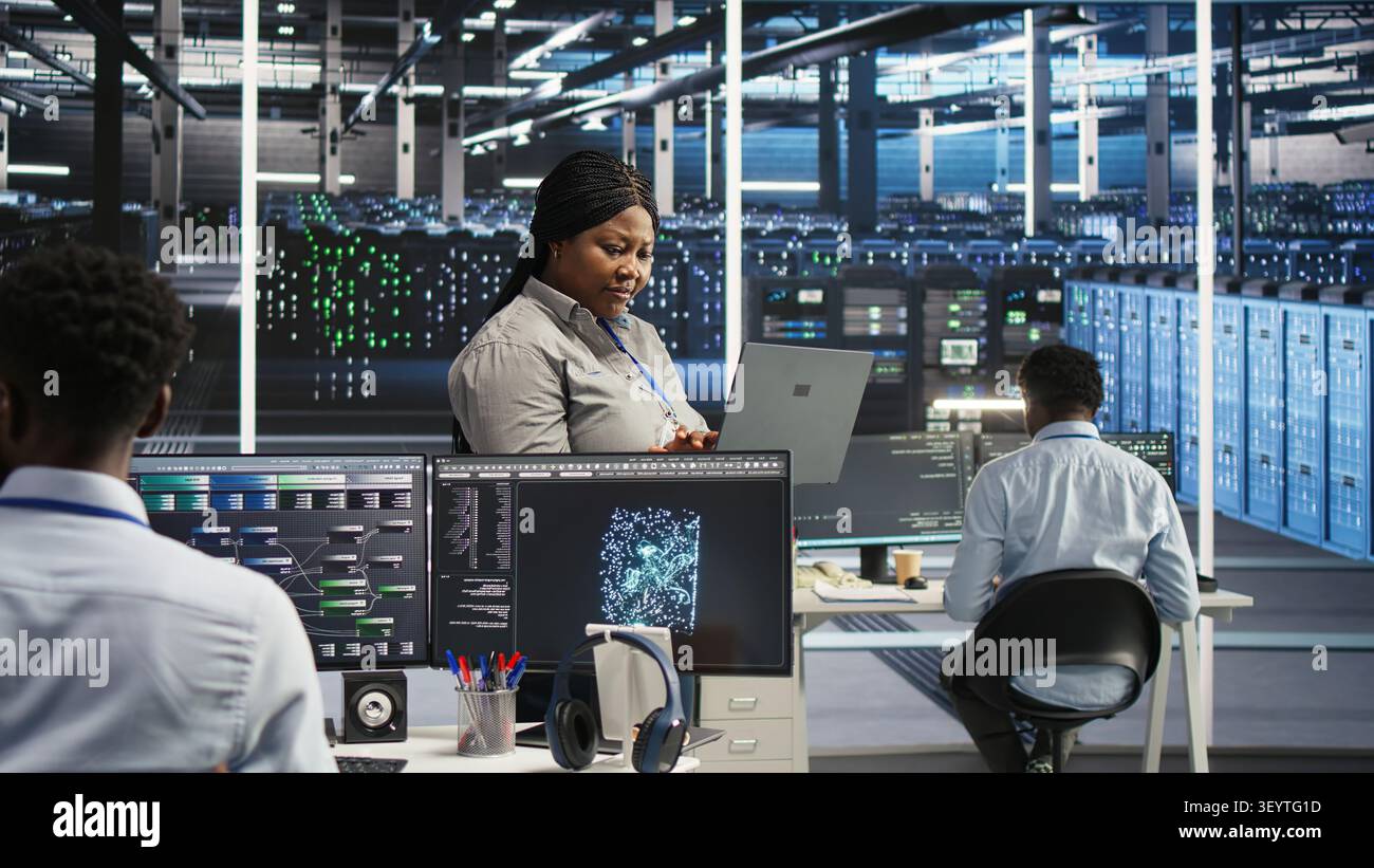 High tech server room system admin working with notebook to do visual programming. Stock Photo