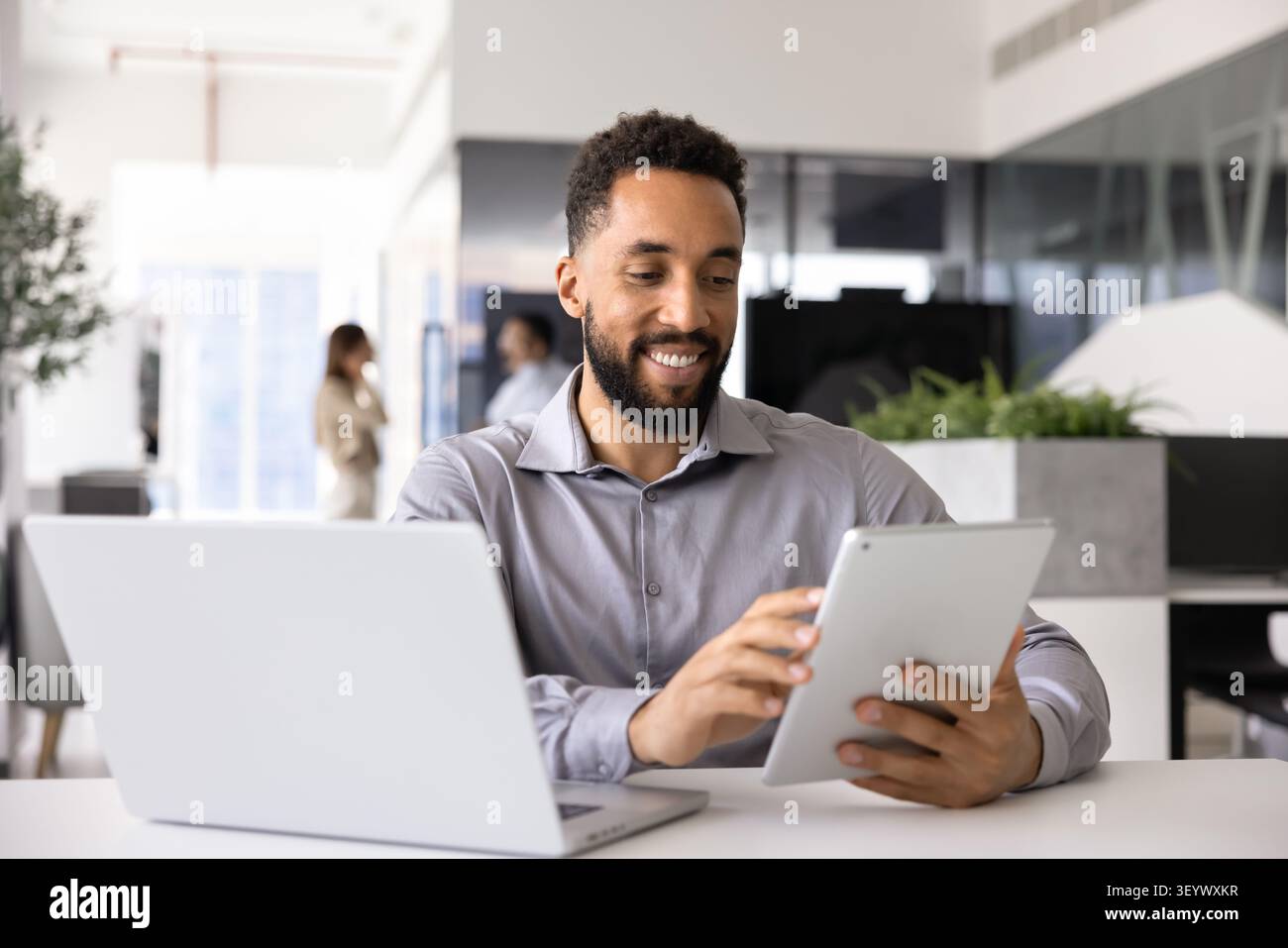 Professional man multitasking with tablet and laptop Stock Photo