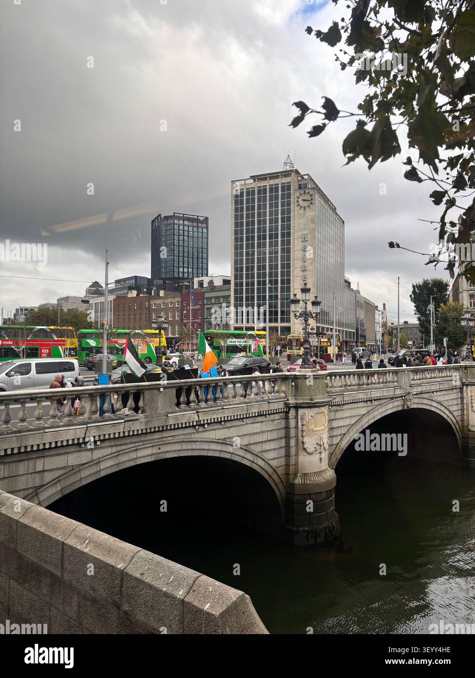 View of the historic stone arch O'Connell Bridge crossing the River Liffey with city skyscrapers in the background, Dublin, Ireland - Smartphone Captured Stock Image