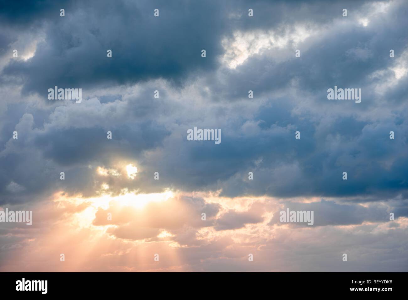 Dramatic sky with clouds and sunlight breaking through at sunset. Stock Photo