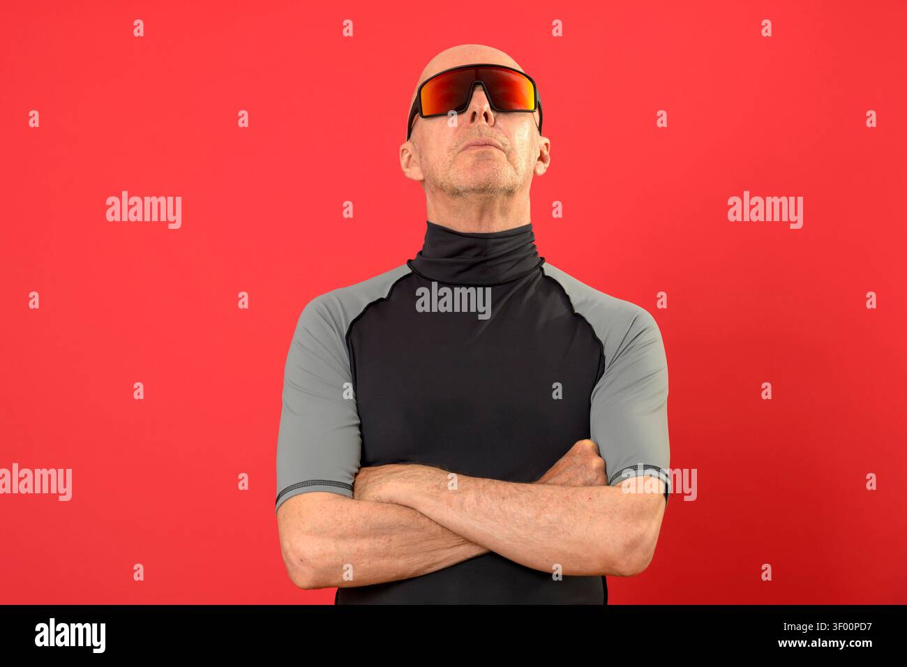 sporty bald man standing with arms folded, looking up Stock Photo
