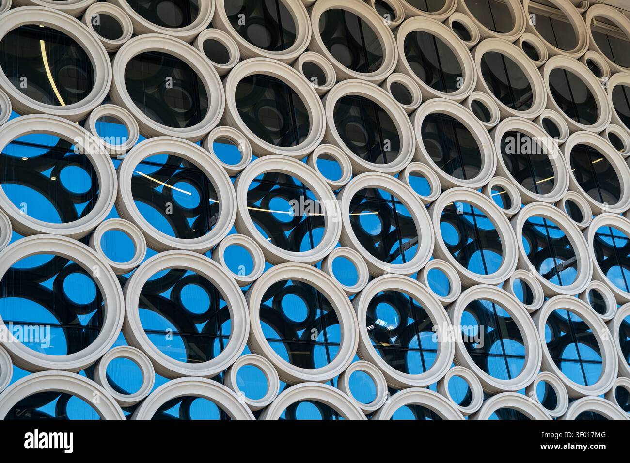 Abstract architectural facade featuring repeated circular frames and large glass windows, creating a geometric pattern with reflections and blue tones Stock Photo