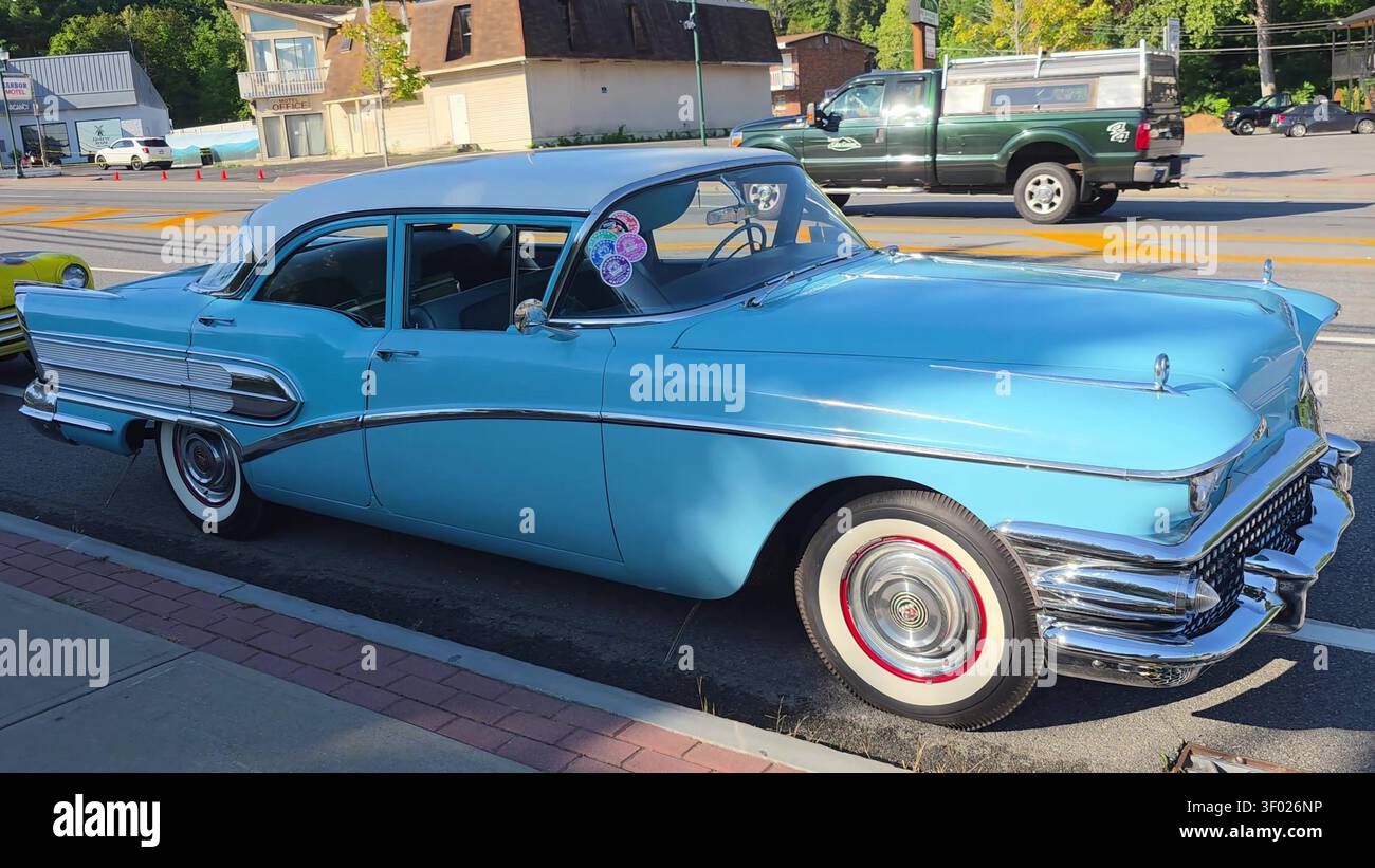 A restored light blue vintage sedan with whitewall tires parked on a street during a car show. Stock Photo