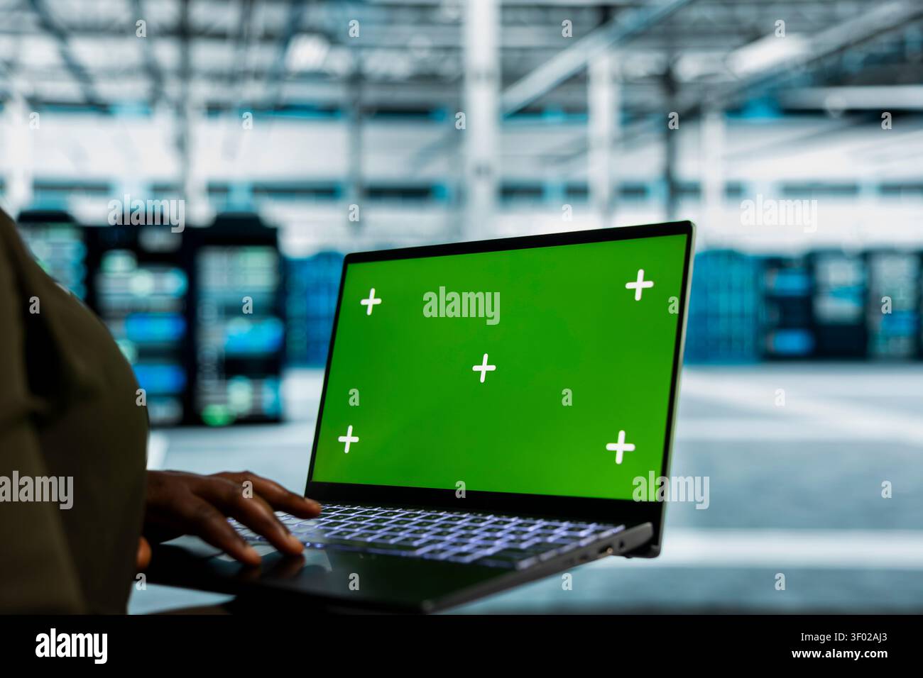 Data center administrator works with a chroma key laptop, using an editable screen to review performance data. Stock Photo
