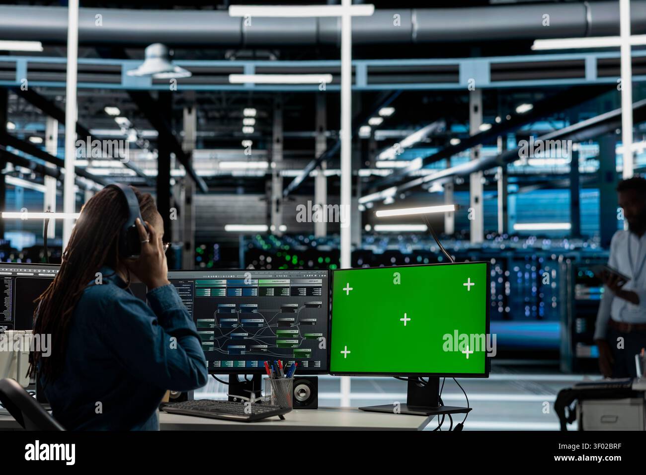 Data center worker works with a chroma key computer, using an editable screen to review performance data. Stock Photo