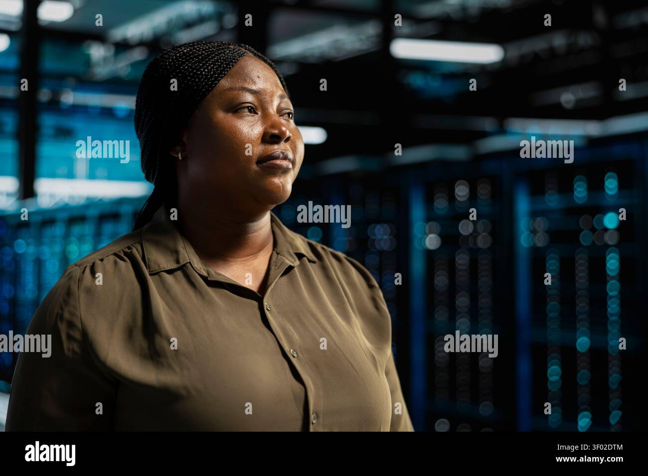 System admin walking in computing facility with server hardware supporting business needs, while doing checkup, ensuring equipment works at optimum operational performance for smooth operations. Stock Photo