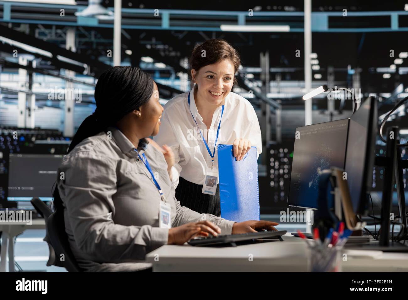 Smiling data center team works with digital devices while reviewing systems, scripts and server infrastructure. Stock Photo