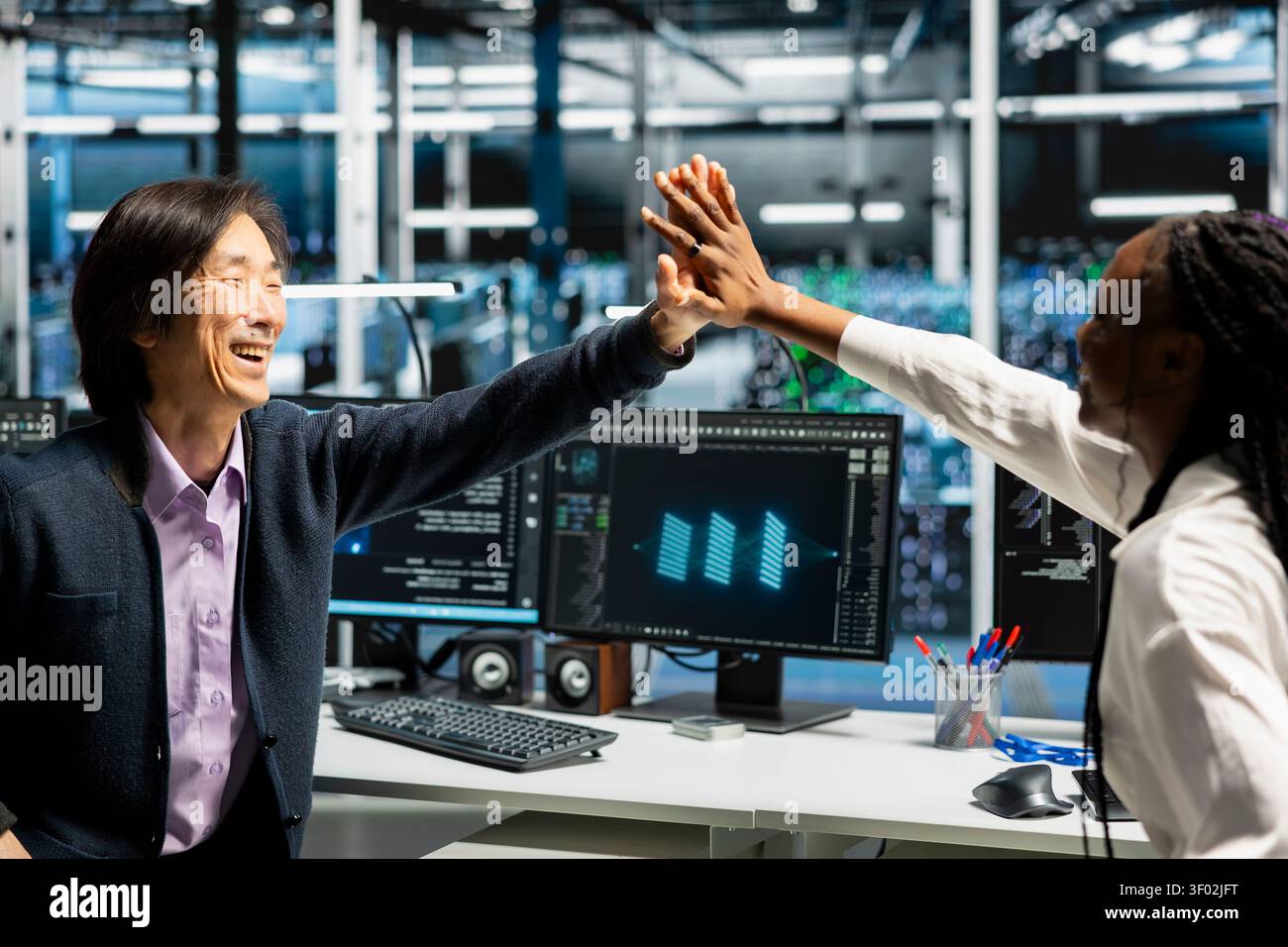 Delighted data center colleagues share a high five after improving system efficiency and completing AI implementation. Stock Photo