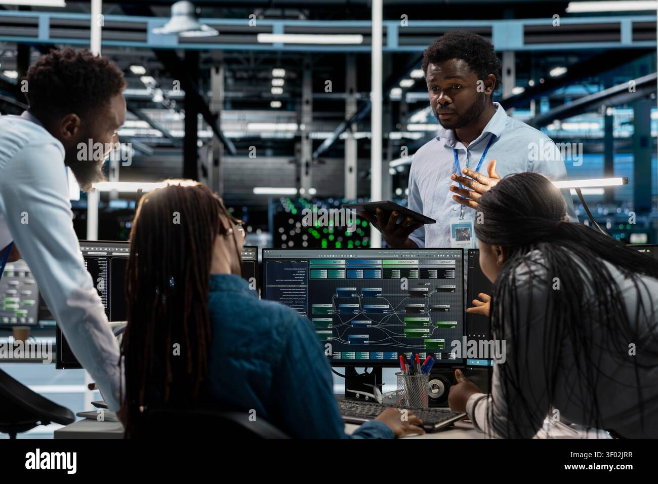 Engineers brainstorm and program inside a server farm, using a PC to repair data center racks and manage computational operations. Stock Photo