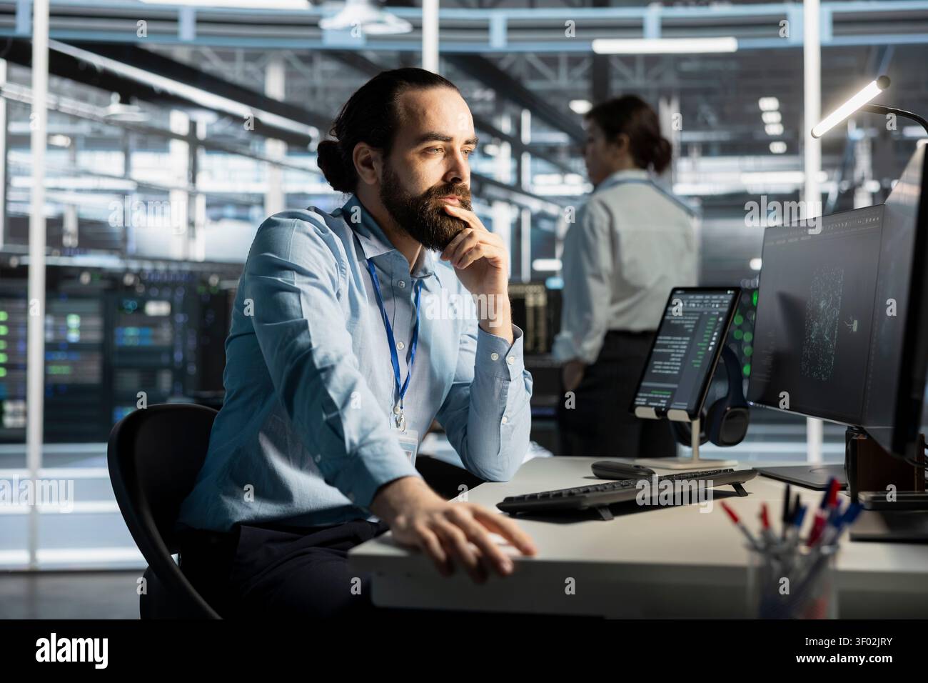 System administrator working with computer in server facility, managing server virtualization, running scripts. Stock Photo
