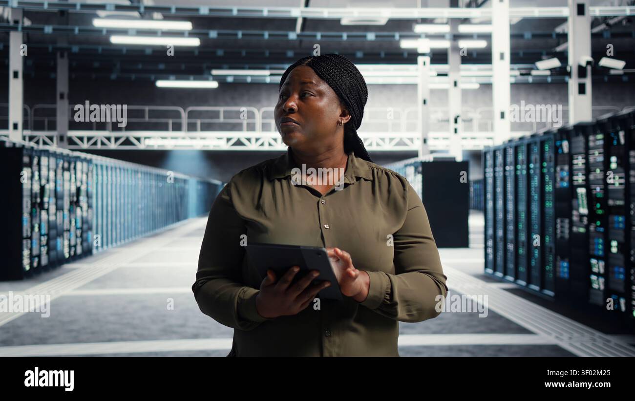Technical specialist working with digital tablet in server facility, integrating new technologies and systems. Stock Photo
