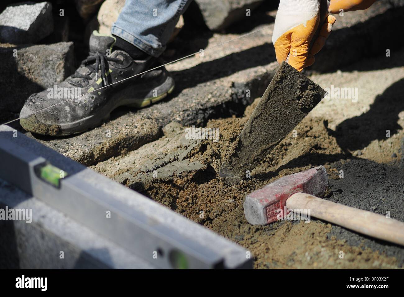 Worker lays concrete in construction area during daytime Stock Photo