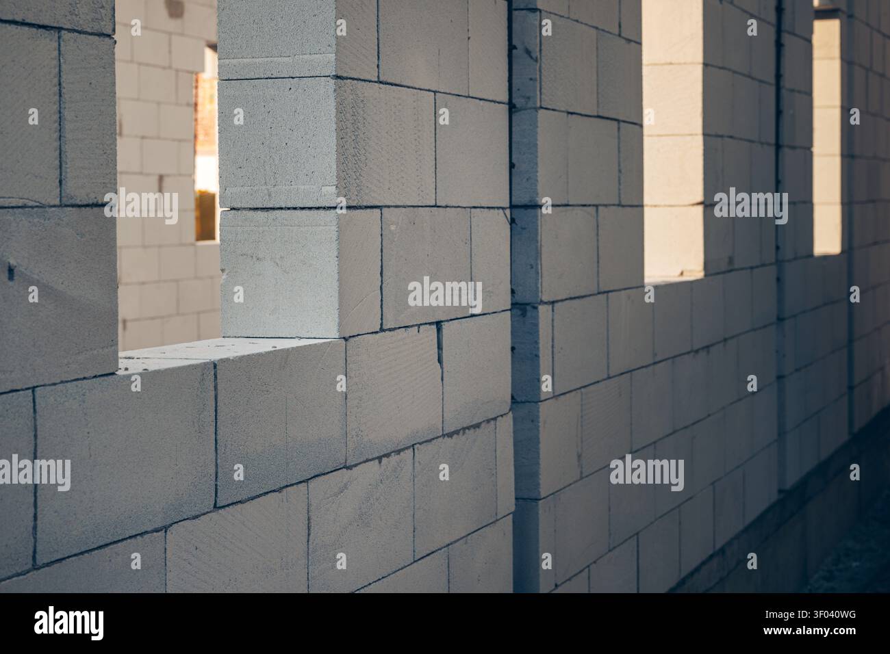Unfinished concrete block wall with rectangular window openings at an indoor construction site, showcasing masonry work, raw materials and industrial Stock Photo