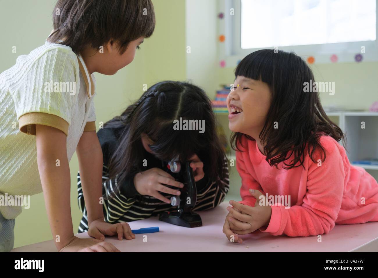 The students are having fun looking through the microscope. Stock Photo