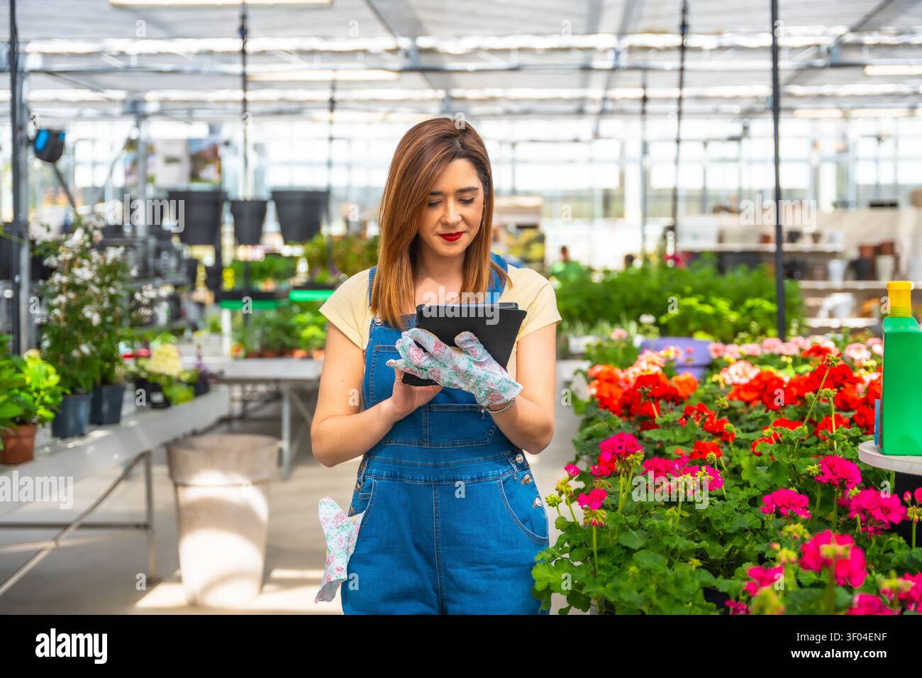 Woman managing greenhouse inventory with digital tablet Stock Photo