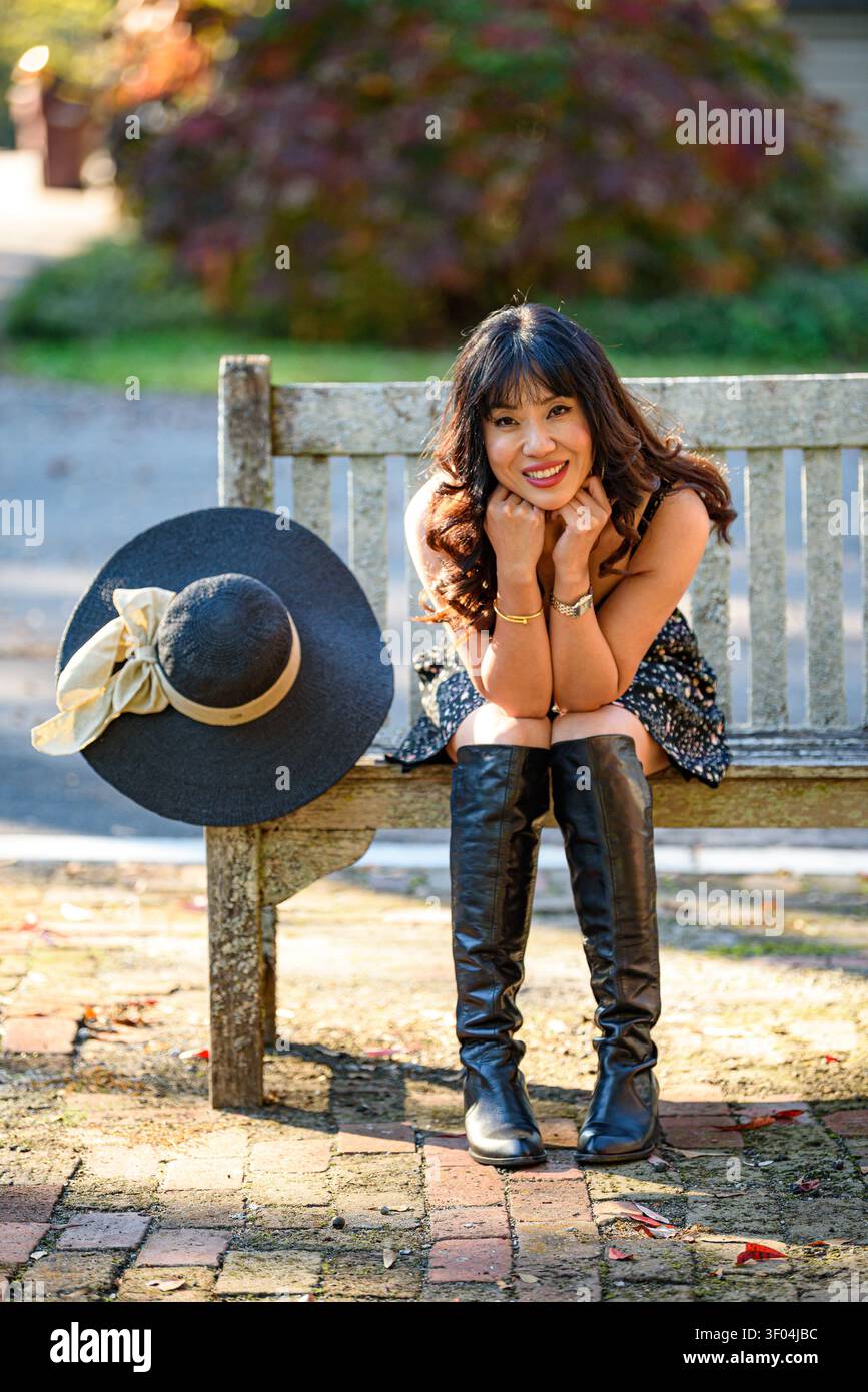 A Smiling Chinese woman sitting on a bench Stock Photo