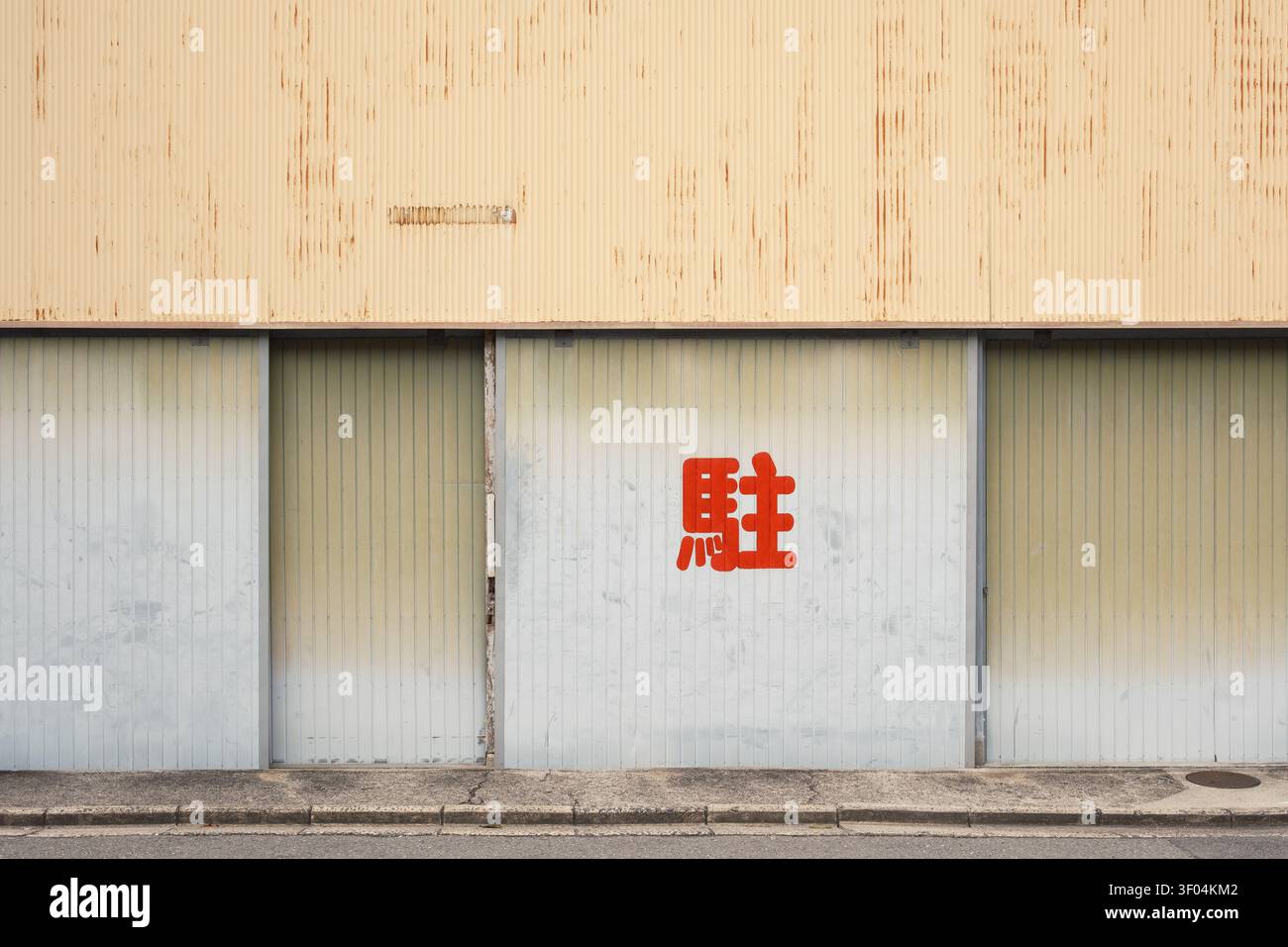 Minimalist exterior wall of a building with closed metal shutters and a single red kanji character script, Kyoto, Japan Stock Photo