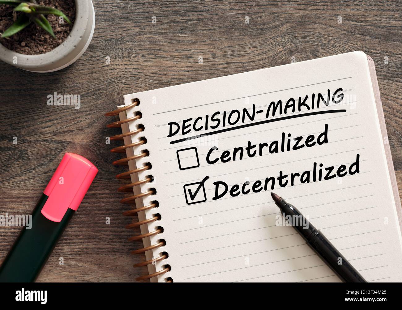 Notebook top view with check boxes for centralized or decentralized decision making, selecting the decentralized option with a marker Stock Photo