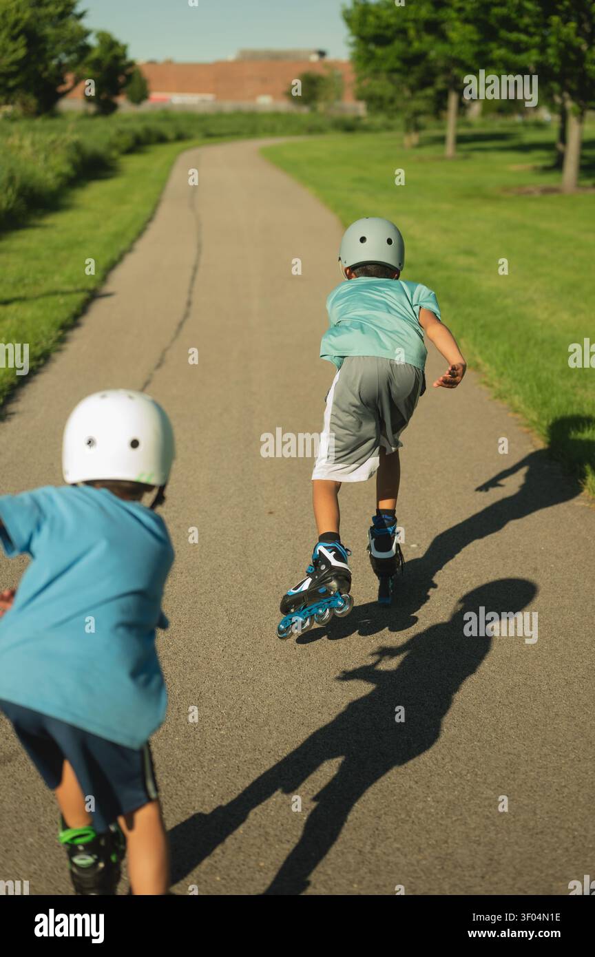 Two boys rollerblading on a path on a sunny day Stock Photo