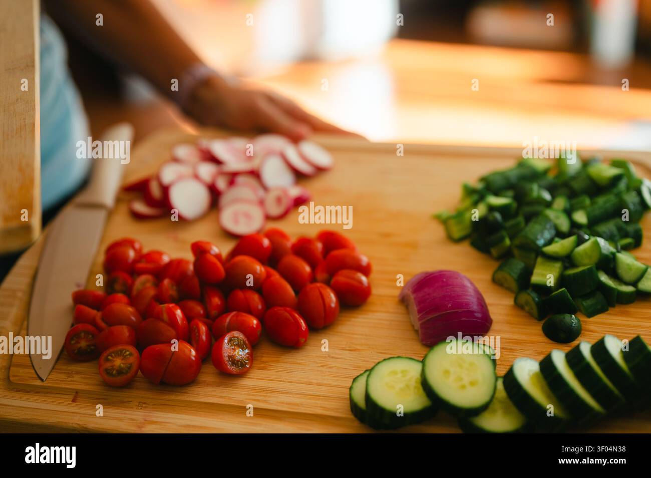 Person preparing fresh vegetables on a cutting board in kitchen Stock Photo