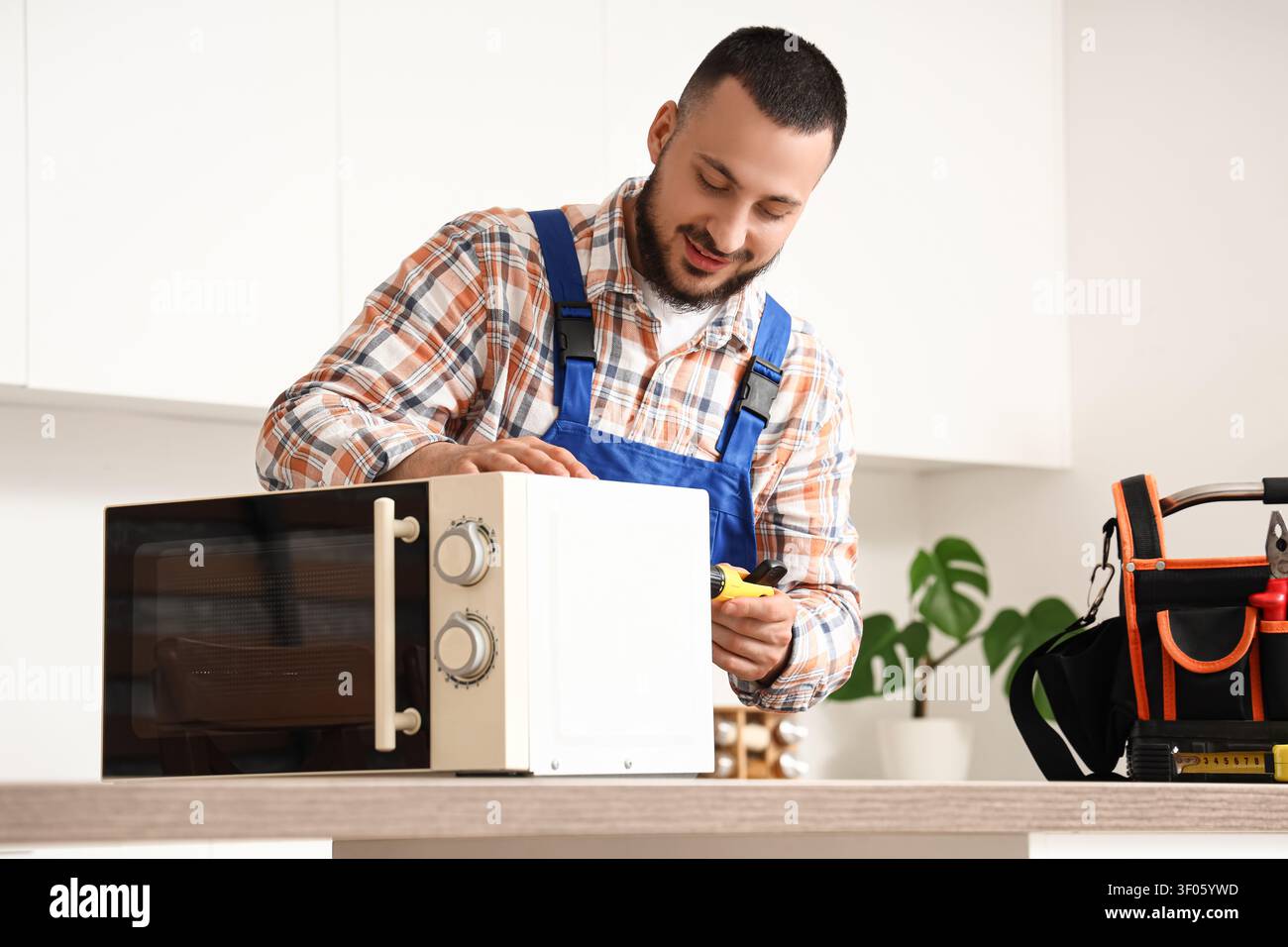 Technician repairing microwave oven in kitchen Stock Photo