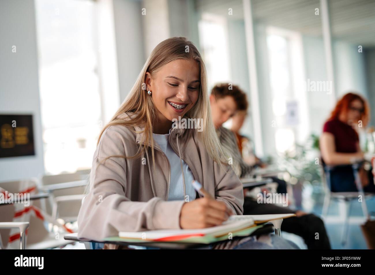 Female student writing notes during university lecture. Stock Photo