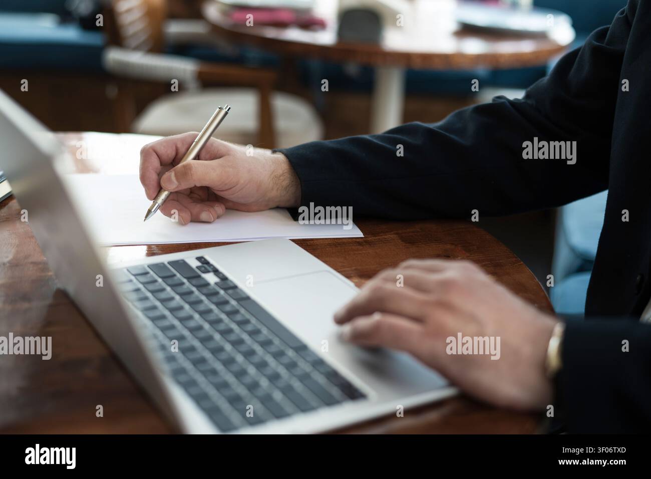 Businessman writing notes while working on laptop Stock Photo