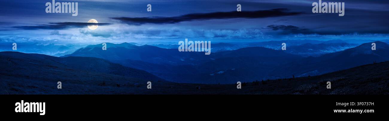 beautiful panorama of mountainous landscape at night. full moon over wide view of cloudy sky over the grassy slope of a mountain ridge. mysterious sum Stock Photo