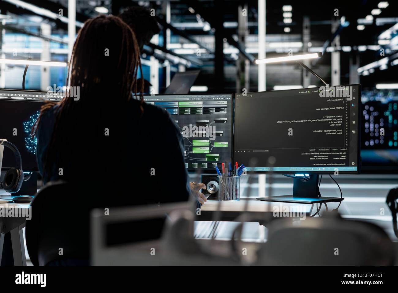 Data center programmer uses a computer to write code for AI systems, working with AI technology and high performance systems. Stock Photo