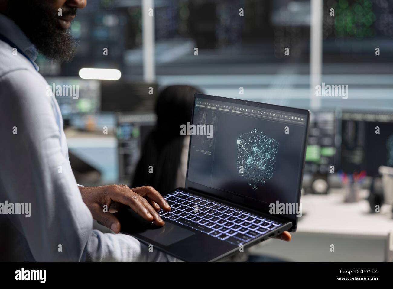 Data center engineer uses a laptop computer in a data center to manage AI virtualization and optimize server infrastructure. Stock Photo