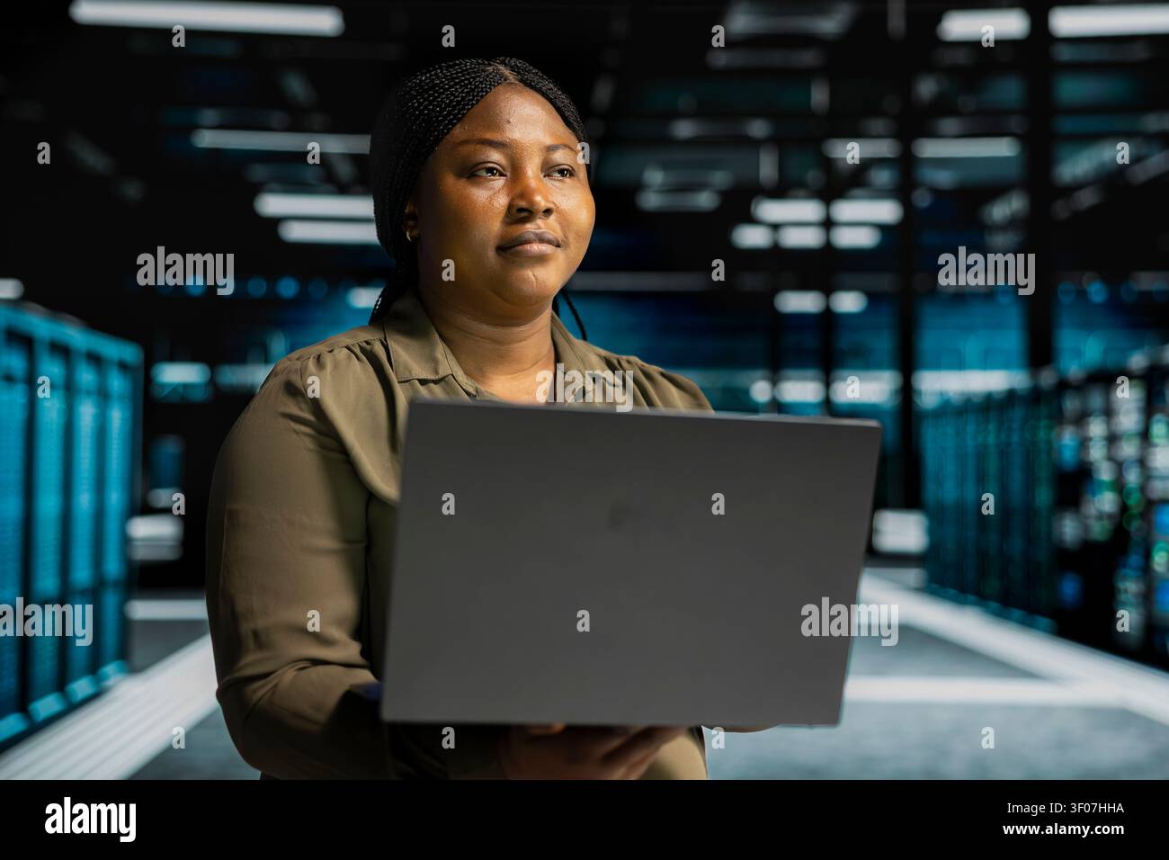 Software engineer works with notebook computer in sustainable server facility, rolling out green technologies. Stock Photo