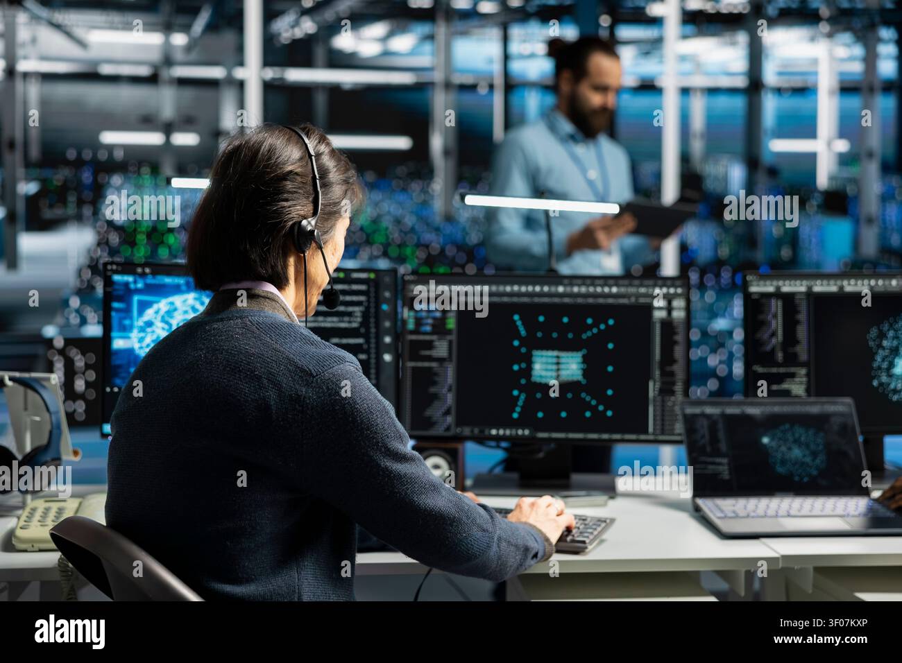 Administrator wears a headset in a server hub, using artificial intelligence troubleshooting to assist users. Stock Photo