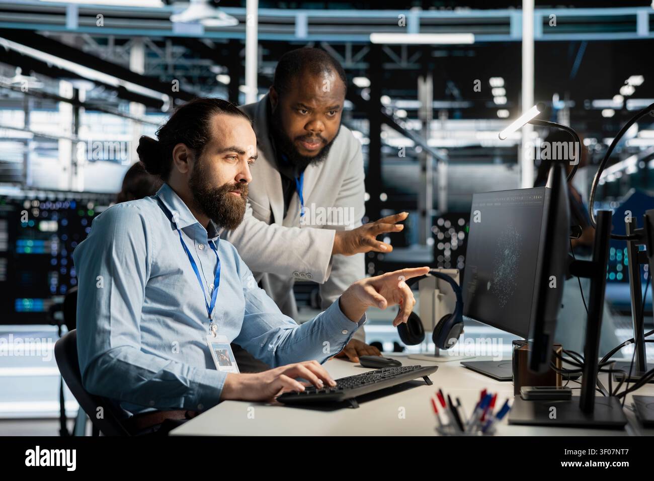 Team of system administrators working with workstation in server environment, analyzing data. Stock Photo