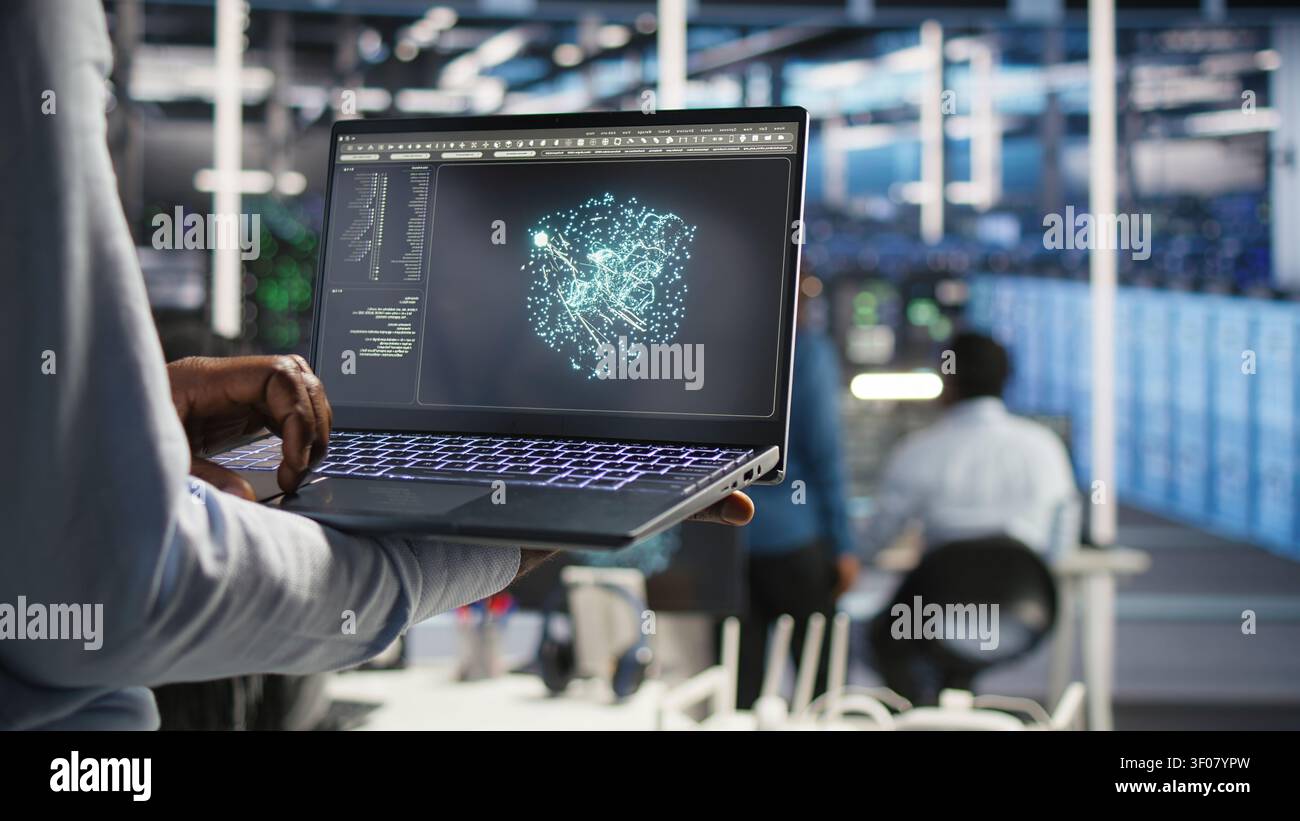Data infrastructure center system admin working with machine learning algorithms on notebook to assess large datasets, while working with AI on notebook to recognize data patterns. Stock Photo