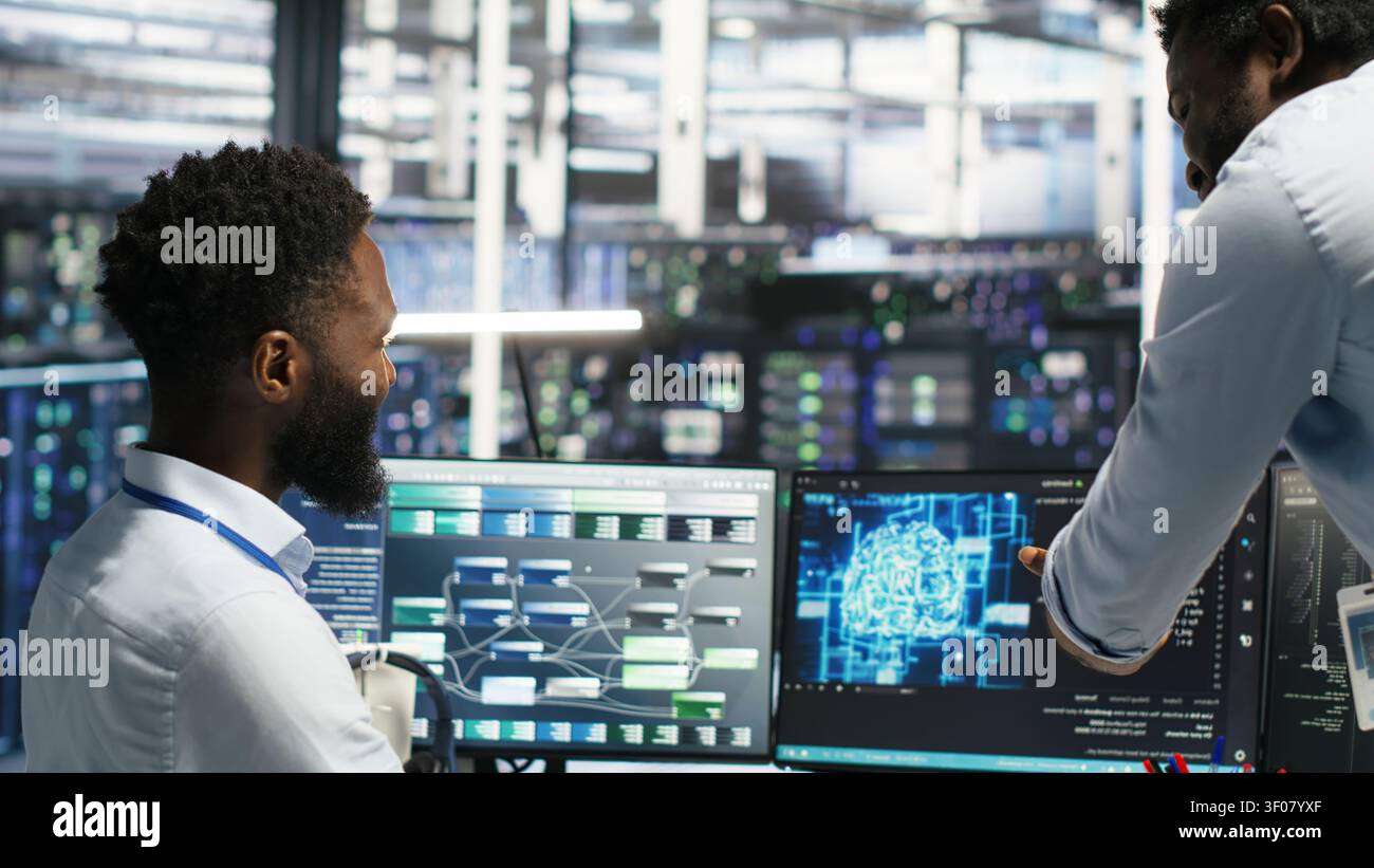 Satisfied server facility supervisor praising technical work from systems engineer working with neural network models to set up hardware. Stock Photo