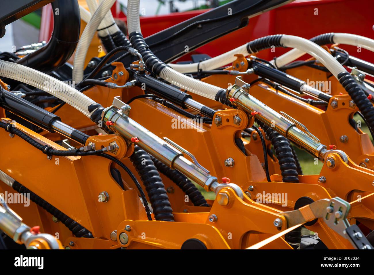 Hydraulic machinery with dual cylinders and metal hoses mounted on an orange reinforced frame. The assembly includes structural supports Stock Photo