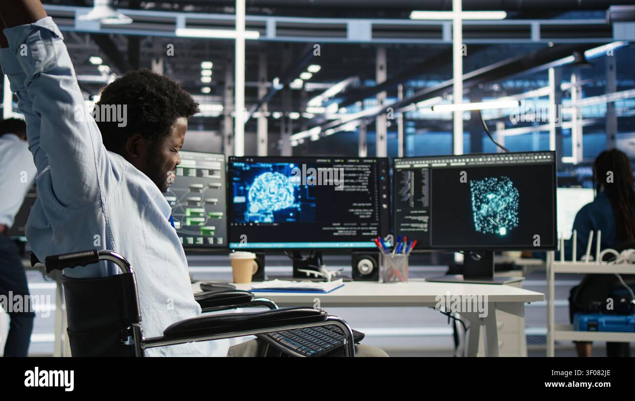 Technical specialist working with wheelchair in data infrastructure center working with AI visual programming system to minimize system downtime with disability working with visual programming. Stock Photo