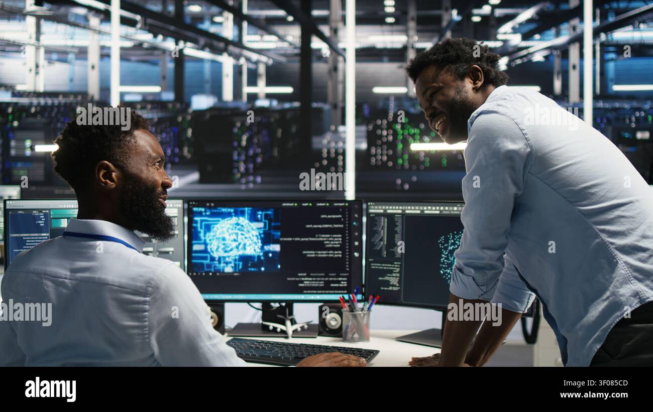 Satisfied server facility supervisor praising technical work from systems engineer working with neural network models to set up hardware. Stock Photo