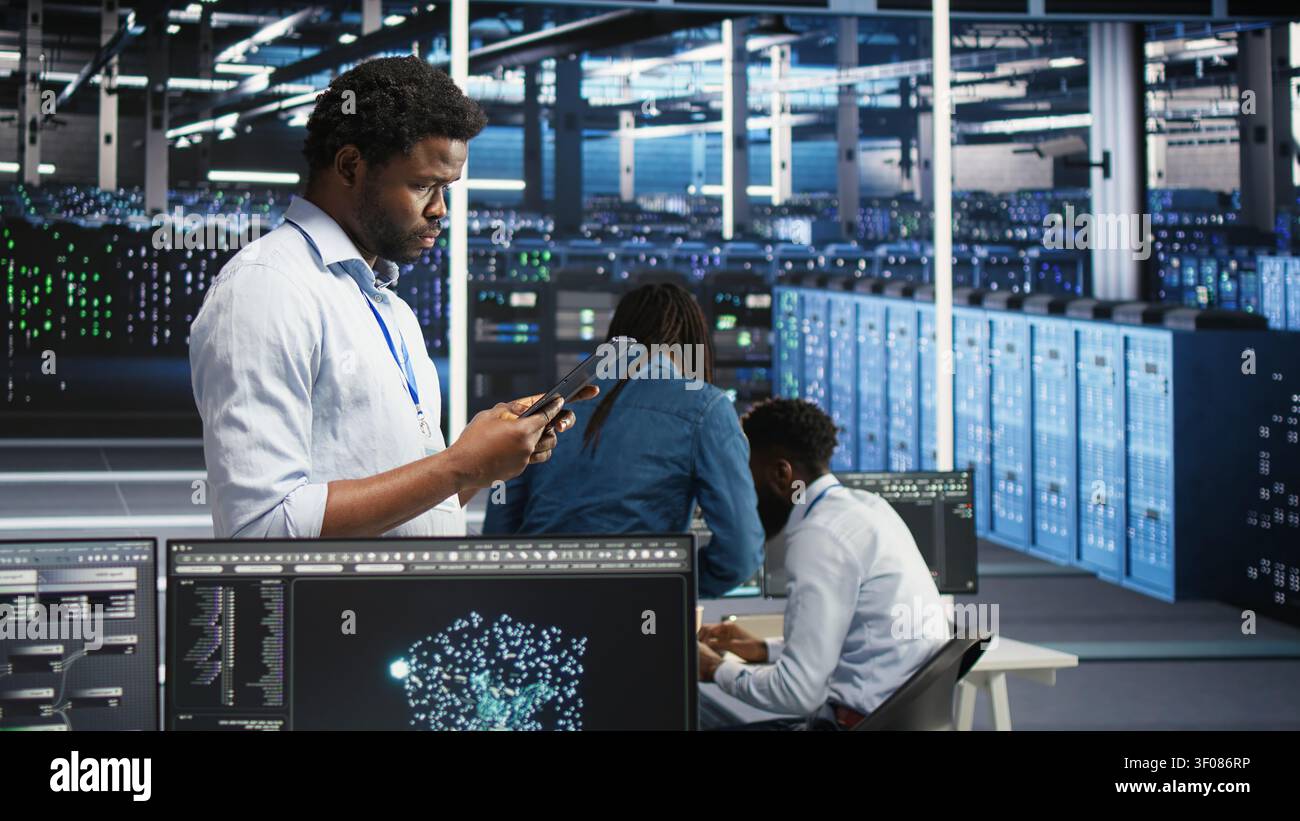High tech server room technical specialist working with digital tablet to interpret AI generated data analytics graphs with working with AI displaying system operational performance predictive. Stock Photo