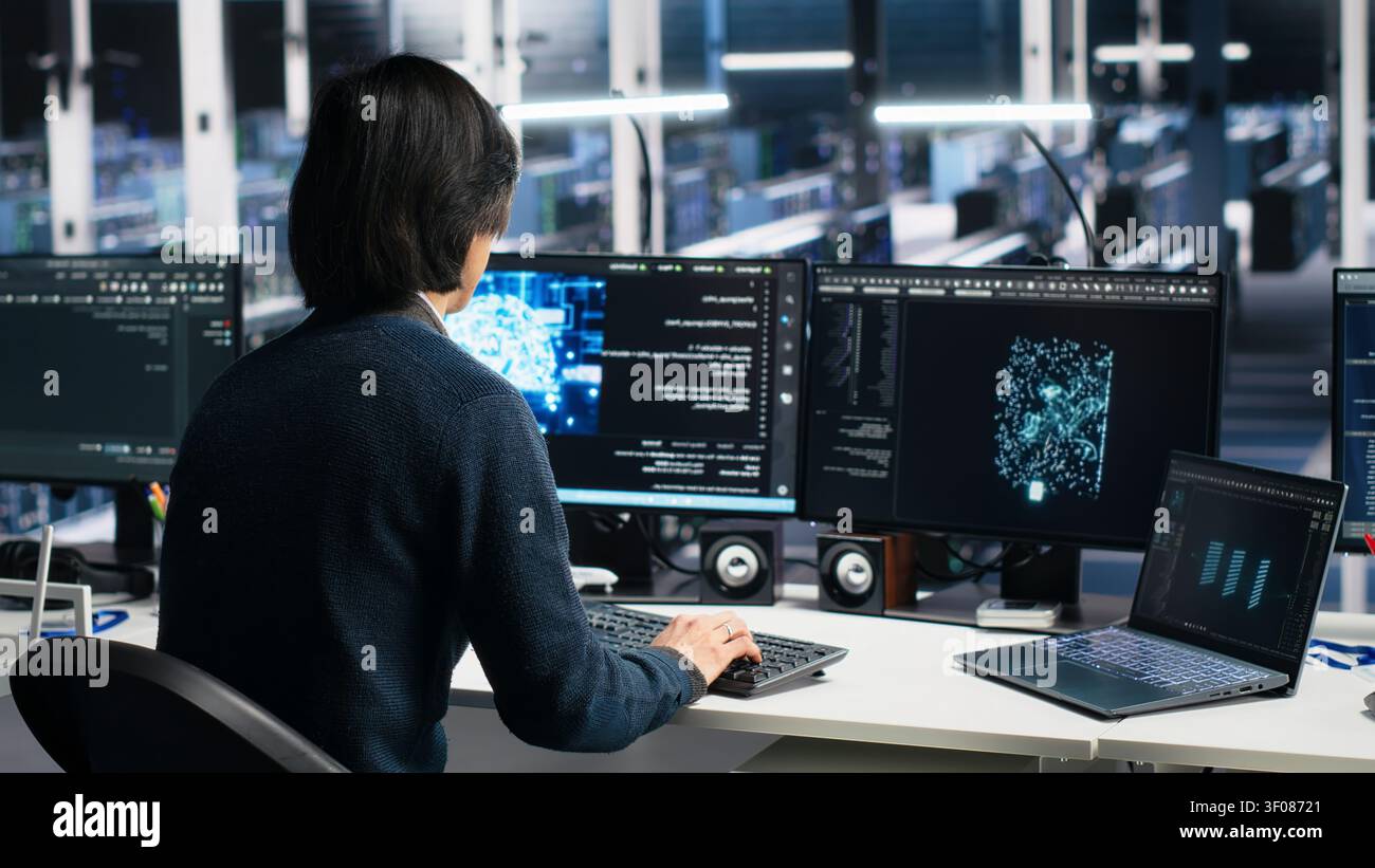 System administrator uses laptop-based deep learning tools in a server room to improve AI operations and system efficiency. Stock Photo