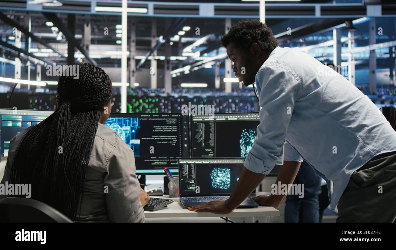 Server facility engineering team works with AI ML models to set up equipment. Teamworking colleagues work on AI programming tools in server environment, optimizing system. Stock Photo