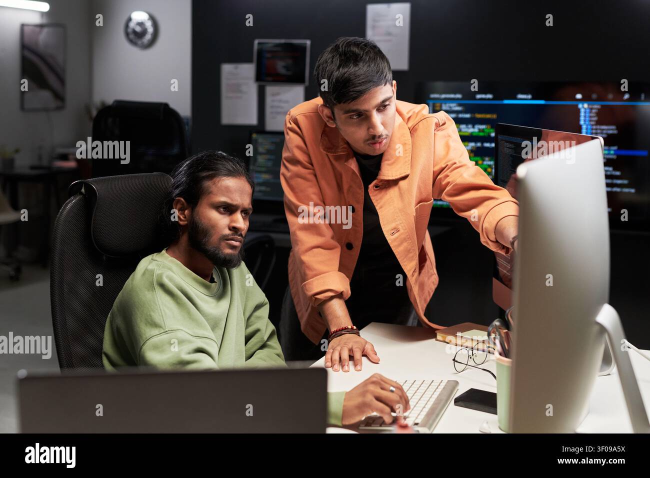 Men Reviewing Software Code on Desktop in Office Stock Photo