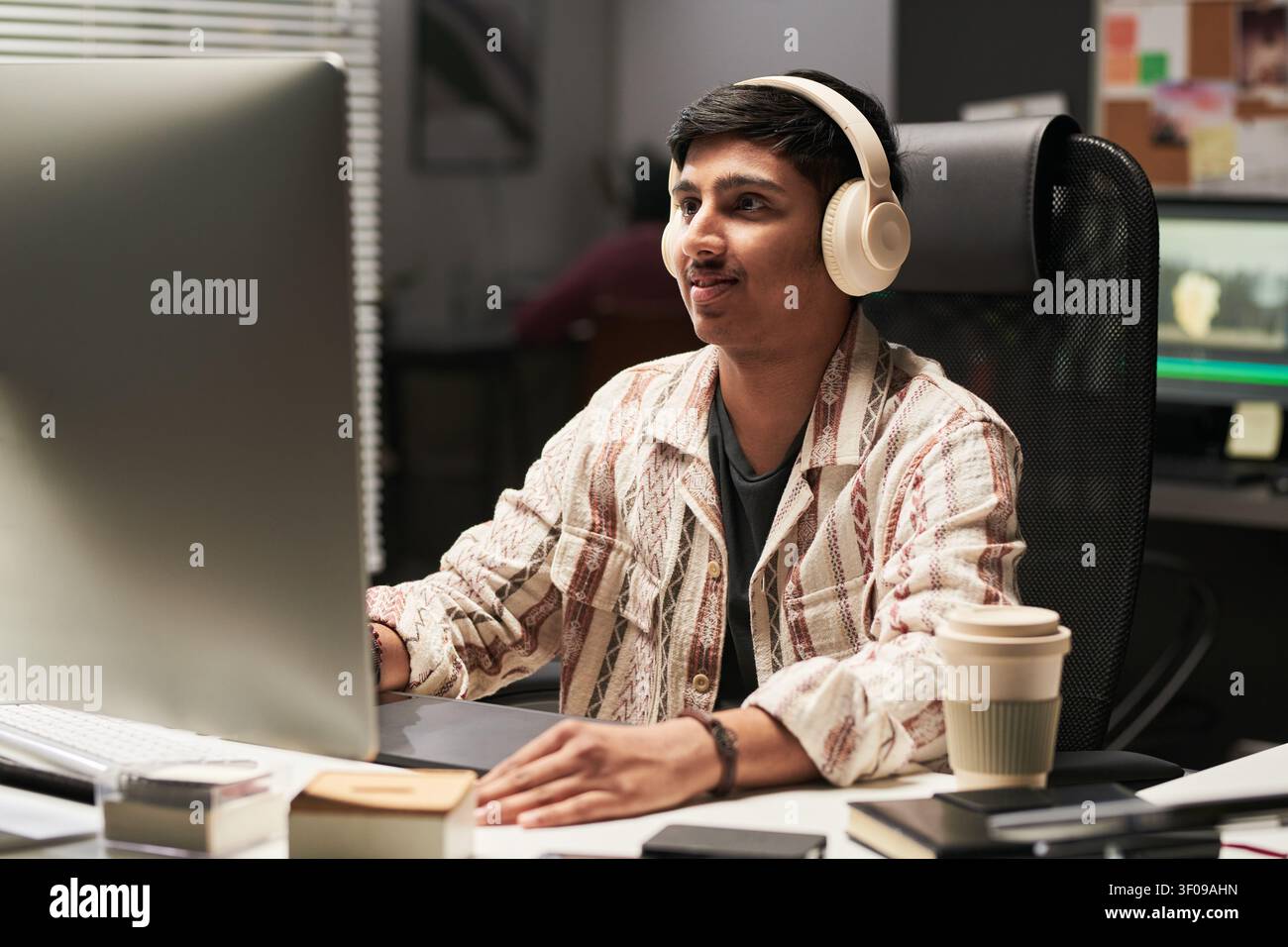 Asian Man Editing Video at Computer in Creative Workplace Stock Photo