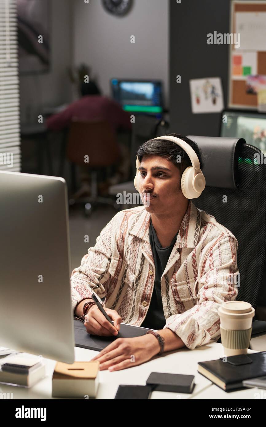 Asian Man Editing Video at Computer in Creative Office Stock Photo