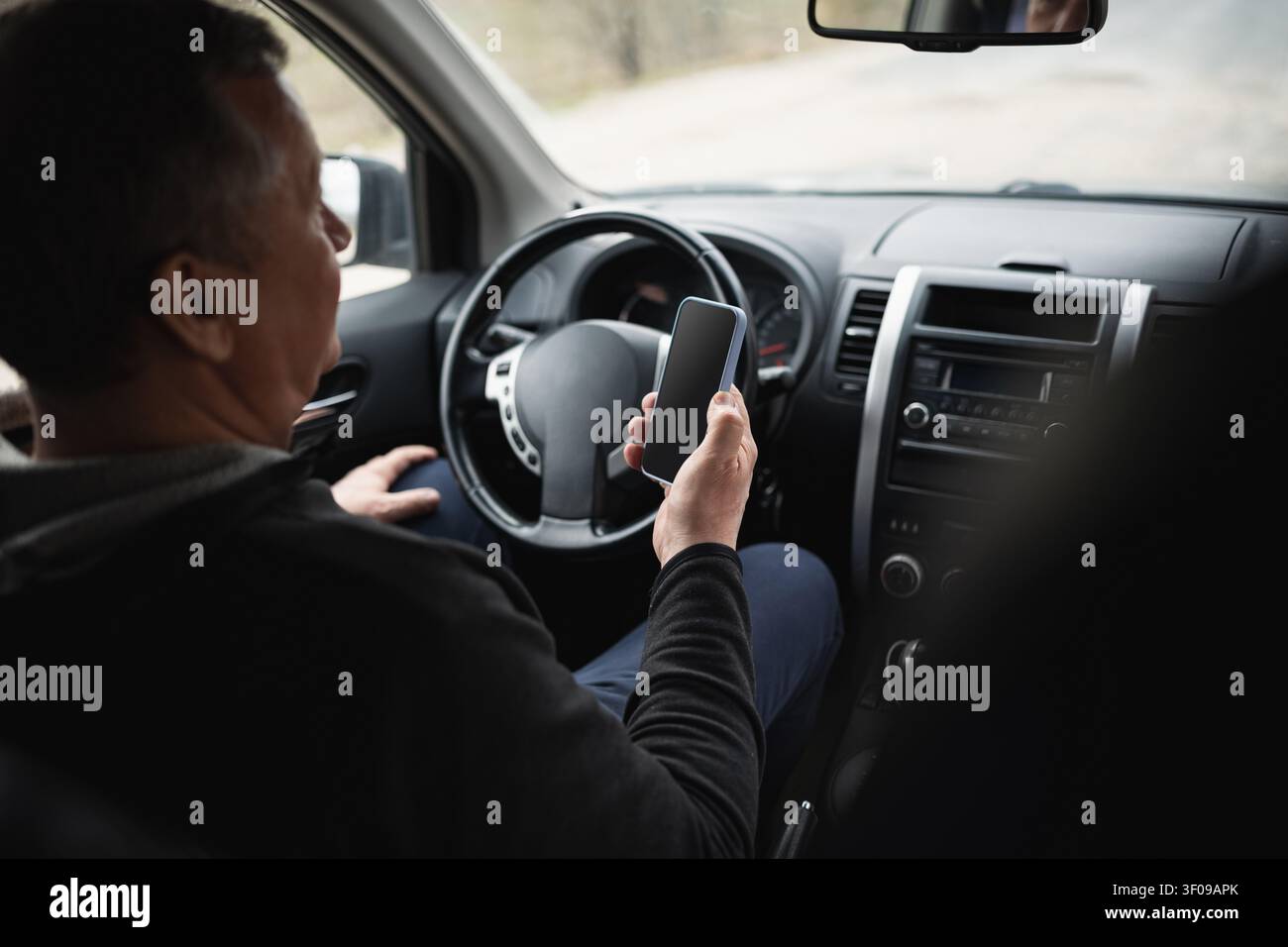 Senior man using smartphone while sitting in parked car Stock Photo